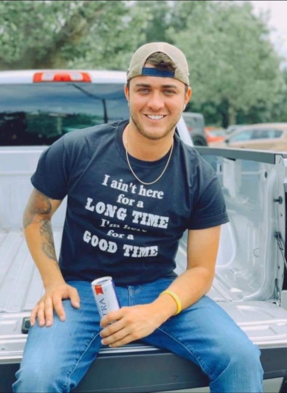 Antony sitting on a truck tailgate, smiling